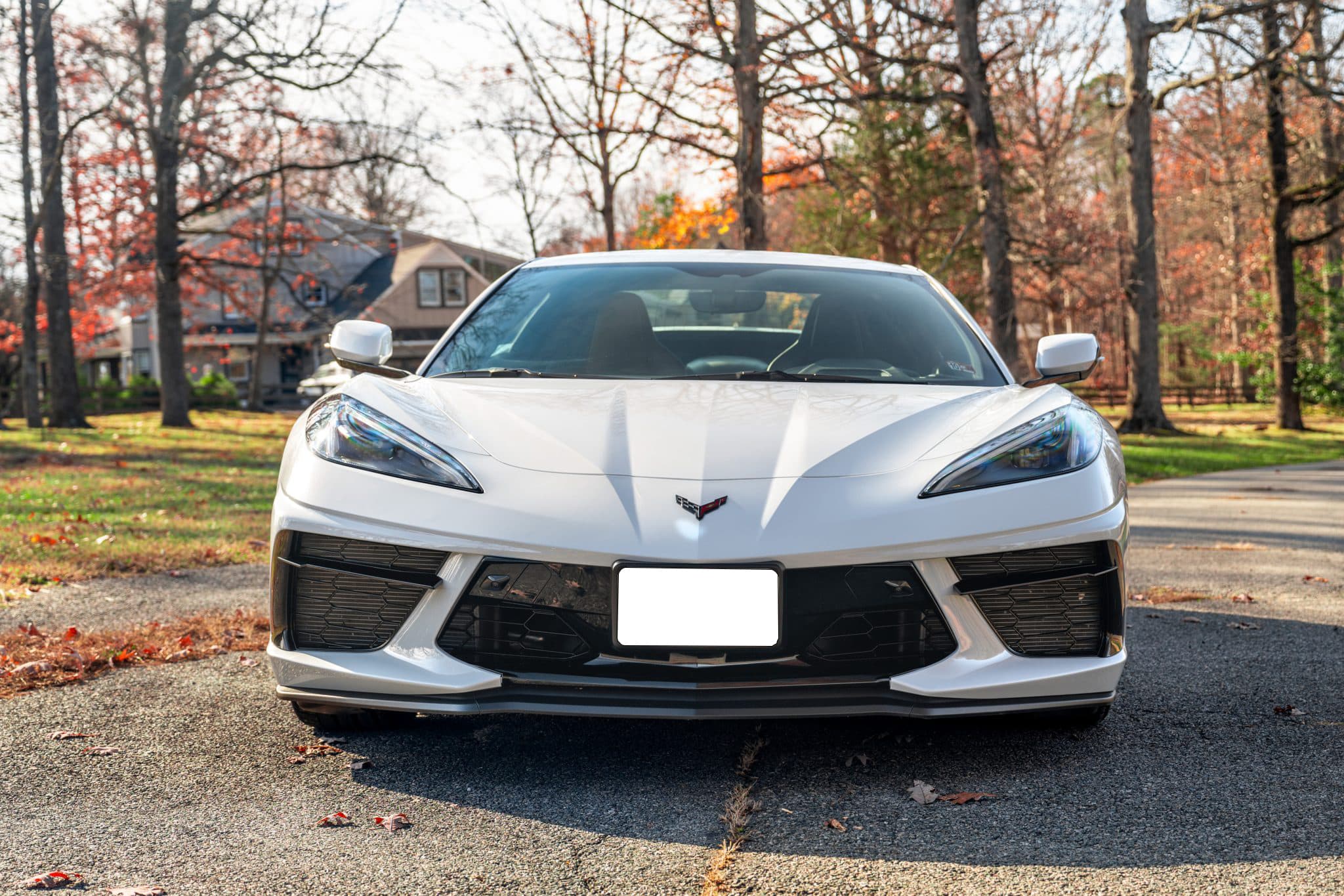 White 2021 Chevrolet Corvette Stingray Convertible photographed head-on with autumn trees behind it.